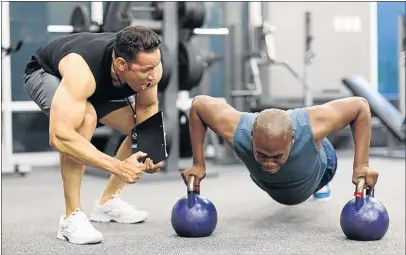  ?? PHOTO:ISTOCK ?? A personal trainer motivates a client doing push-ups. The writer says you are likely to achieve fitness nirvana if you have a gym buddy.