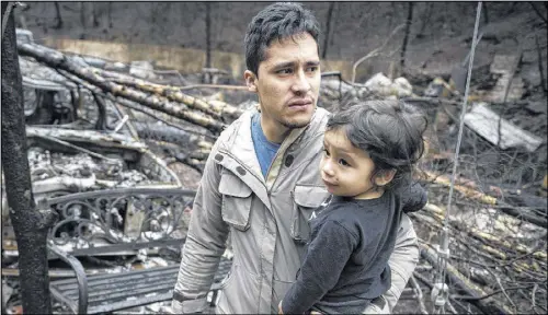  ?? PHOTOS BY ANDREW NELLES / AP ?? Allan Rivera holds onto his son Nathan Rivera, 23 months old, as he looks at the remains of their home for the first time Monday in Gatlinburg, Tenn. The family evacuated from their rental cabin before it was destroyed by a wildfire.