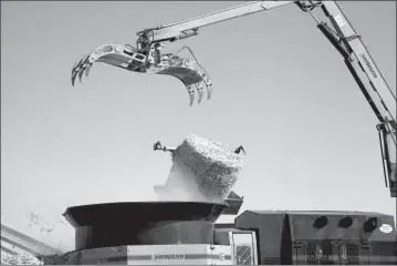  ?? Donnis Hueftle-Bullock ?? At right, a large bale of hay looks small as it’s dropped into a grinder with a Haybuster machine.