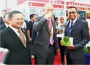  ??  ?? Taste test: Dr Ong trying out a product while making his rounds at the Malaysia Pavilion during the 15th China-Asean Expo in Nanning. Looking on is Malaysian consulate-general in Nanning Bong Yik Jui (left).