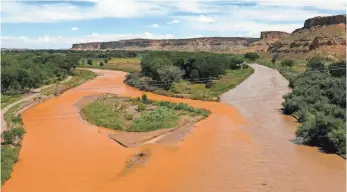  ?? JON AUSTRIA, THE DAILY TIMES ?? Tainted water flows from the Animas River, left, and into the San Juan River. The spill has shut off irrigation canals, which has prompted the Navajo Nation to consider suing the EPA.