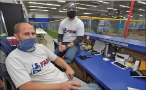  ??  ?? Dan Watson/ The Signal (Above) Co-owners Gino Camilleri, left, and Shawn Davis discuss their business at The Farm SCV — an 8,000-square-foot, six batting lane baseball and softball training facility in Santa Clarita on Friday. (Right) Manager Shannon Amary hangs paper to cover the windows at The American Barbershop in Stevenson Ranch on Friday. Both Santa Clarita Valley businesses opened in January only to face months of on-and-off closures due to pandemic restrictio­ns. These SCV business owners and others are struggling to find a way to continue operating, most without having received any federal or state COVID-19 relief.