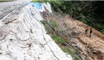  ?? — Bernama photo ?? Workers in Seremban carry out works to stabilise a slope along Jalan Pesiaran Senawang 3 following a landslide which caused cracks to appear on the road.