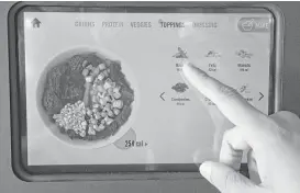  ??  ?? A customer chooses ingredient­s for a salad on the touchpad of the robot at the Calafia Cafe in Palo Alto, Calif.