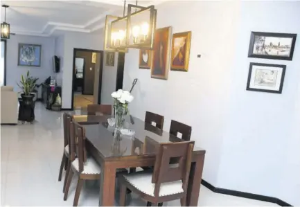  ?? Kitchen ?? Dining area with industrial-style chandelier. The table is made from teak and has stood the test of time with the top protected by glass.