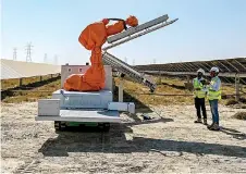  ?? ?? Workers operating a machine during the installati­on of a solar panel.