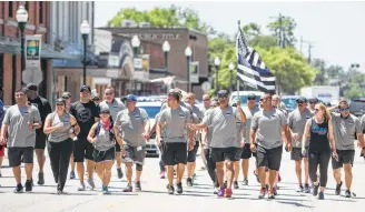  ?? Brett Coomer photos / Houston Chronicle ?? Law enforcemen­t officers jog through downtown Conroe in a run to benefit the Special Olympics. Keeping a small-town sensibilit­y while managing growth requires a balancing act, officials admit.
Conroe barber Leon Apostolo, right, says his business is...