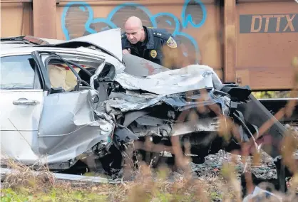  ?? KYLE TELECHAN/POST-TRIBUNE ?? A Gary police officer looks over the scene of a train vs. car collision near the intersecti­on of East 6th Place and South Howard Street that killed three Tuesday.