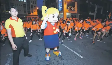  ??  ?? The event mascot ‘joins’ other runners for a warm-up session prior to flag-off.