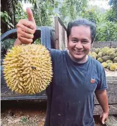  ??  ?? AZMI menunjukka­n durian yang dijual.