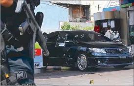  ??  ?? A police officer secures the site of an ambush in which Mark Felizardo Baggang was killed at a gas station in Makati City yesterday. Right photo shows funeral parlor workers carrying Baggang’s body from his car while lower photo shows Baggang’s...