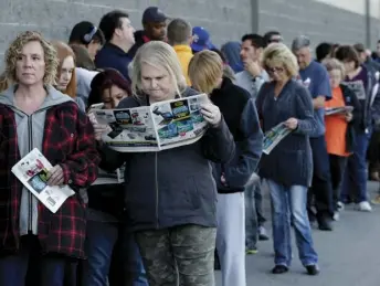  ?? AP PHOTO/CHARLIE RIEDEL ?? People wait in line for a Best Buy store to open for a Black Friday sale on Thanksgivi­ng Day, Thursday in Overland Park, Kan. Shoppers are hitting the stores on Thanksgivi­ng as retailers under pressure look for ways to poach shoppers from their rivals.