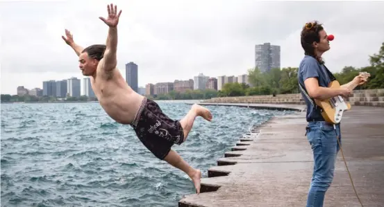  ?? ASHLEE REZIN GARCIA/SUN-TIMES ?? Dan O’Conor, who calls himself the Great Lake Jumper, dives into Lake Michigan near Montrose Harbor while guitarist Cam Mahai sings “EndTimes.”