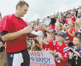  ?? STAFF PHOTO BY JOHN WILCOX ?? HAPPY HAPPY: Tom Brady signs autographs for lucky fans yesterday in Foxboro.