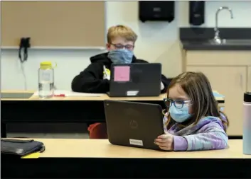  ?? AP PHOTO/TED S WARREN ?? In this Feb. 2 file photo, students wear masks as they work in a fourth-grade classroom, at Elk Ridge Elementary School in Buckley, Wash. After seeing two academic years thrown off course by the pandemic, school leaders around the country are planning for the possibilit­y of more distance learning next fall at the start of yet another school year.