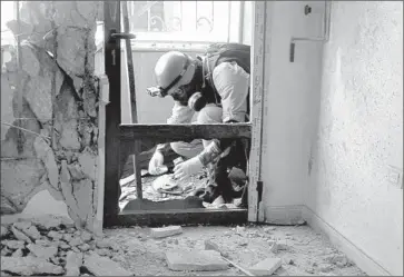  ?? AMMAR AL- ARBINI/ GETTY- AFP PHOTO ?? A U. N. arms expert collects samples where rockets fell in Ghouta, a suburb of Syria’s capital. A report could take days.