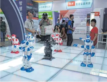  ?? FOTO: AFP ?? Keine Angst vor dem blinkenden Bruder: In China werden schon ganz kleine Kinder an Roboter herangefüh­rt. Die neueste Erfindung soll den Babysitter und die Geschwiste­r ersetzen.