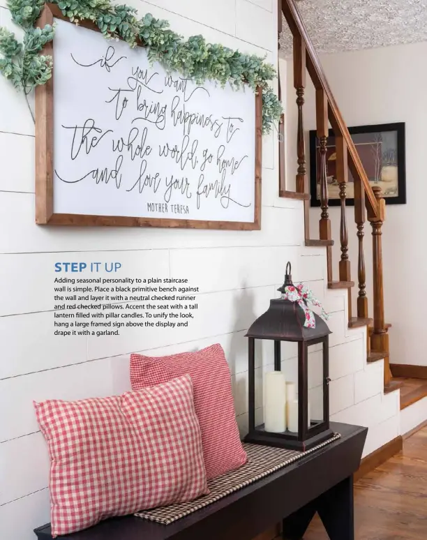  ??  ?? STEP IT UP
Adding seasonal personalit­y to a plain staircase wall is simple. Place a black primitive bench against the wall and layer it with a neutral checked runner and red checked pillows. Accent the seat with a tall lantern filled with pillar candles. To unify the look, hang a large framed sign above the display and drape it with a garland.