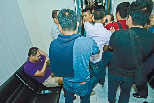  ?? SUNSTAR FOTO / AMPER CAMPAÑA ?? IN CUSTODY. Police officers secure Bohol Provincial Board Member Rey Niño Boniel when Angela Leyson (partly hidden, in shades) confronts him at the Police Regional Office 7 headquarte­rs. Leyson is a close friend of his wife.