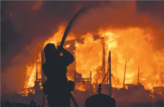  ?? NATURE’S FURY: A firefighte­r douses flames as a home burns in the Napa wine region of California. The blaze has destroyed 1500 homes. Picture: JOSH EDELSON ??