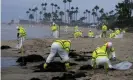  ?? HW Chiu/AP ?? Workers in protective suits clean the contaminat­ed beach in Corona Del Mar after an oil spill off the southern California coast, on 7 October 2021. Photograph: Ringo