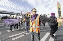  ?? ELAINE THOMPSON / ASSOCIATED PRESS ?? Service Employees Internatio­nal Union staffer Sam Finkelstei­n holds back traffic during a march by demonstrat­ors in favor of a minimum wage of $15 an hour and union shops near Seattle-Tacoma Internatio­nal Airport on Nov. 29.