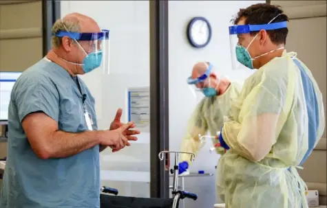  ?? Amanda Chambers/University of Alabama at Birmingham via AP ?? Dr. Michael Saag, left, speaks with a co-worker Friday in Birmingham, Ala. Dr. Saag survived COVID-19 and now treats patients with the disease.