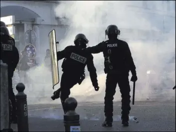  ?? Claude Paris The Associated Press ?? Riot police officers kick back a tear gas grenade during a protest Saturday in the southern French city of Marseille.