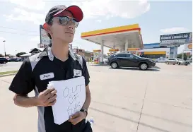  ?? AP Photo/Tony Gutierrez ?? n Employee Bryan Herrera holds a makeshift sign that reads, “Out of Gas,” as he stands outside the Shell filling station where he works Thursday in North Dallas. Some Texas stations are out of fuel and pump costs are spiking. A major gasoline pipeline...