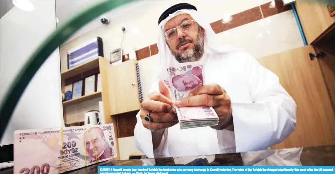  ??  ?? KUWAIT: A Kuwaiti counts two-hundred Turkish lira banknotes at a currency exchange in Kuwait yesterday. The value of the Turkish lira dropped significan­tly this week after the US imposed sanctions against Ankara. — Photo by Yasser Al-Zayyat