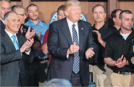  ?? JIM WATSON/AFP/GETTY IMAGES ?? Surrounded by miners, U.S. President Donald Trump applauds after signing the executive order rolling back climate protection­s enacted by Barack Obama. Canada’s oilsands sector is focusing on innovation­s that reduce emissions because they help reduce...