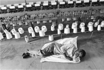  ?? PHOTO: REUTERS ?? A worker takes a nap during a power cut in front of yarn-spinning equipment inside a factory in Coimbatore.