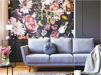  ?? ?? GETTY IMAGES The large-scale pattern and bold colors of this floral wallpaper make a dramatic statement against the neutral gray furnishing­s in this dark living room.