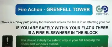  ??  ?? Signs: A poster in the tower block tells residents to ‘stay put’ in the event of a fire