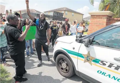  ?? STEPHEN M. DOWELL/ORLANDO SENTINEL ?? Protest organizer Miles Mulrain Jr. raises an arm as he yells in front of a sheriff ’s deputy vehicle outside a home Friday in Windermere. The home is owned by Derek Chauvin, the Minneapoli­s police officer who was videotaped kneeling on the neck of George Floyd before Floyd’s death.