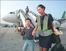  ?? WANG HUA / VISUAL CHINA ?? A crew member of budget carrier Spring Airlines accompanie­s a boy traveling himself at Dalian airport, Liaoning province.