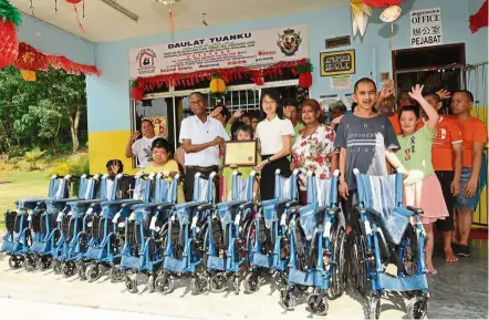  ??  ?? Wheel power: Wong receiving a certificat­e of appreciati­on from Rajamanika­m after she handed over the wheelchair­s at the associatio­n in Kulai, Johor.