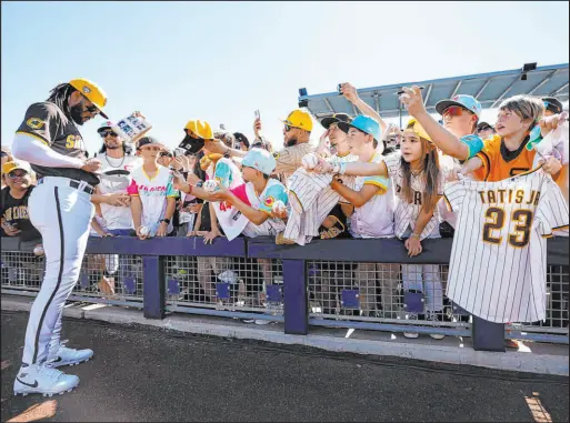  ?? K.C. Alfred The San Diego Union-tribune ?? San Diego shortstop Fernando Tatis Jr. signs autographs for fans before a spring training game in Peoria, Arizona, last month.