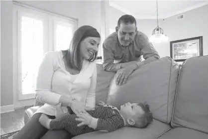  ?? Associated Press ?? ABOVE: Lauren NievesTara­nto, left, and husband Francisco play with their youngest child, Nicolas, 4-months, on Feb. 7 at their home in Windermere, Fla. Francisco Nieves-Taranto covered the entire $8,000 bill from the birth of Nicolas last year with his...