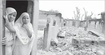  ?? Pius Utomi Ekpei AFP/Getty Images ?? STUDENTS linger in the remains of a Maiduguri school burned in 2012 by Boko Haram. The group believes that Earth is f lat, Muslims may take slaves and secular education pushes a harmful Western agenda.