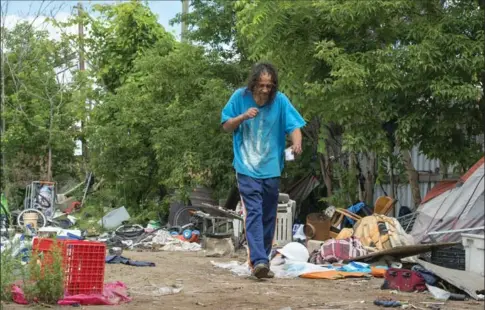  ??  ?? Michael Fanning moves among the discarded material in a lot at the corner of Stuart and Caroline streets. A clutch of homeless men has been living there under tarps.