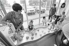  ??  ?? Julie Sondag pours plastic balls down a slide as children play and learn at Gymboree Play & Music in Norman.