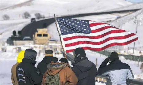  ?? Jim Watson/AFP/Getty Images ?? Activists and U.S. veterans stand by a police barricade Sunday on a bridge near Oceti Sakowin Camp on the edge of the Standing Rock Sioux Reservatio­n outside Cannon Ball, N.D.