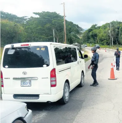  ?? PHOTO BY HOPETON BUCKNOR ?? Motorists slow to a halt as police man a checkpoint in Westmorela­nd.