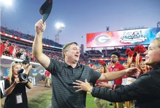  ?? The Associated Press ?? ■ Georgia head coach Kirby Smart, center, is greeted by his wife Mary Beth Smart, right, after a win over Florida in an NCAA football game on Oct. 30 in Jacksonvil­le, Fla.