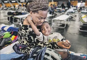  ?? John Burgess Press Democrat ?? BERNADETTE YABADI and her son Victor rest at a Red Cross shelter at the Sonoma County Fairground­s in Santa Rosa after strong winds pushed the Kincade fire to the south, forcing them to evacuate.