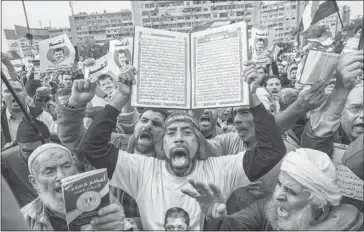  ?? Daniel Berehulak/getty Images ?? A man holds up a Qur’an as supporters of Egyptian President Mohamed Morsi and members of the Muslim Brotherhoo­d chant slogans during a rally Friday in Cairo. Opponents and supporters of Morsi staged final rallies in Cairo ahead of Saturday’s referendum...