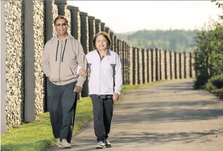  ?? DON MOLYNEAUX ?? Karan and Vas Menon enjoy a walk down the pathway near their new home in Heartland by Apex Developmen­ts in Cochrane.