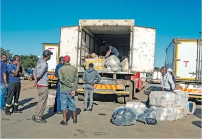  ?? Picture: AFP ?? DISTRIBUTI­ON CENTRE. Men wait beside a trailer which has just arrived in Harare from South Africa, carrying groceries, among other goods for families depending on these rations.