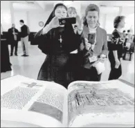  ?? St. Louis Post-Dispatch/TNS/CHRISTIAN GOODEN ?? Sister Marysia Weber (left), Paula Pfeiffer and Laura Lato look at pages of a bound copy of a section of the St. John’s Bible on display at headquarte­rs of the Archdioces­e of St. Louis.